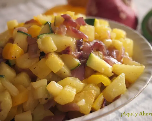 Un delicioso salteado de verduras con patatas, calabacín y pimientos amarillos, con trozos de cebolla morada.