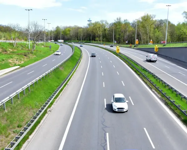 Autostrada z kilkoma samochodami i zielonymi pasami.
