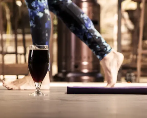 Szklanka ciemnego piwa obok maty do ćwiczeń. Czy to koniec treningu, czy nagroda? Alkohol a siłownia – dylemat.
