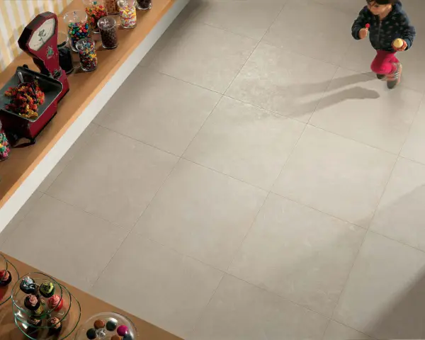 Un enfant court sur un sol carrelé 60x60. L'épaisseur du joint du carrelage est subtile, soulignant la modernité de la pose.