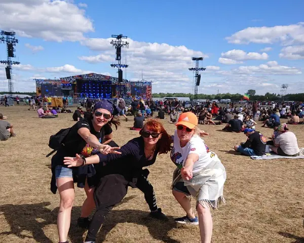 Trzy kobiety bawią się na festiwalu czaplinek pol and rock. W tle scena i tłum ludzi.