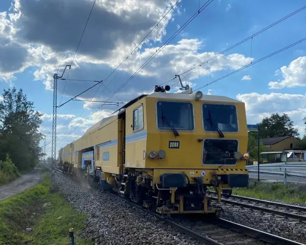 Żółta maszyna torowa DORA jedzie po torach w okolicach Częstochowy. Może to być element rozkładu jazdy prac torowych w Blachowni.