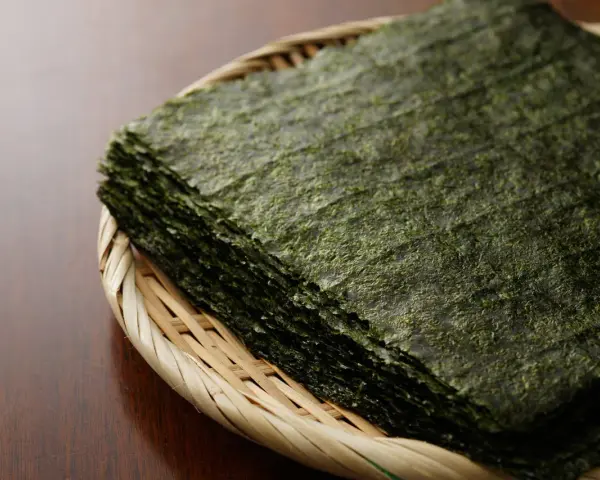 Feuilles d'algue nori empilées dans un panier en osier. Attention, certaines algues peuvent contenir des traces de métaux lourds, un danger potentiel.