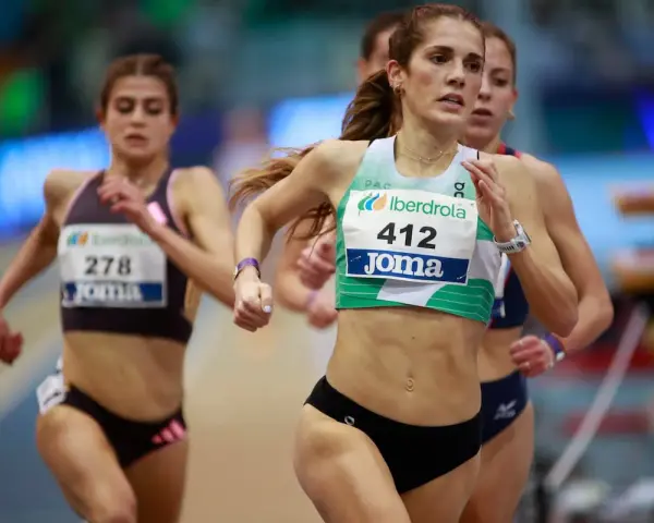 Corredoras en competición de atletismo femenino España. La atleta con el dorsal 412 lidera la carrera, mostrando su determinación.