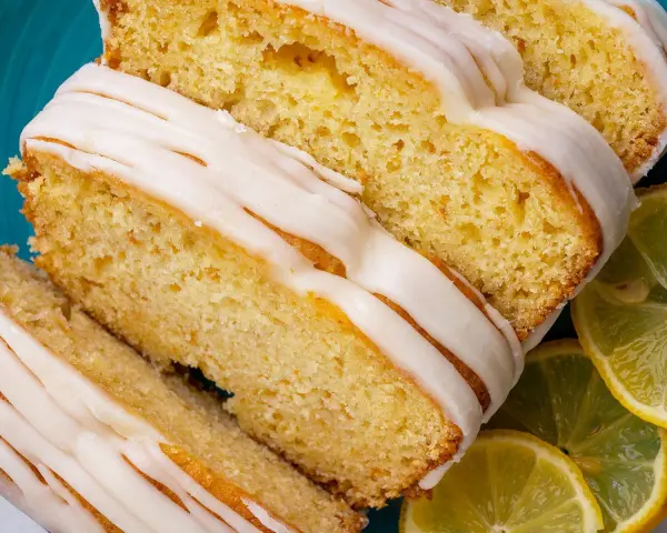 Saftiger Zitronenkuchen mit Zuckerguss, perfekt für einen sonntagskuchen schnell und einfach. Dazu frische Zitronenscheiben.