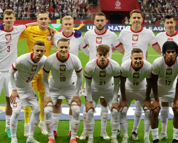 Piłkarze reprezentacji Polski w białych strojach, gotowi do gry. Wszyscy z orzełkiem na piersi, czekają na dobry wynik Polska.