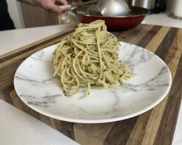 Un plato de spaghetti aglio e olio, con perejil picado, listo para disfrutar.