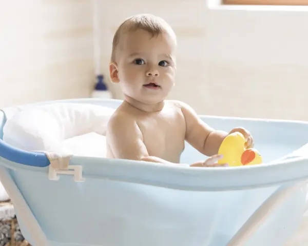 Urocze dziecko w niebieskiej wanience z żółtą kaczką. Kąpiel w wanience jest świetną zabawą, a dziecko może w niej przebywać, dopóki nie zacznie samodzielnie siadać i wstawać.