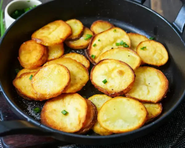 Goldbraune Bratkartoffeln mit Salz und Schnittlauch in einer Pfanne. Ein einfaches Bratkartoffeln Rezept für jeden Tag.