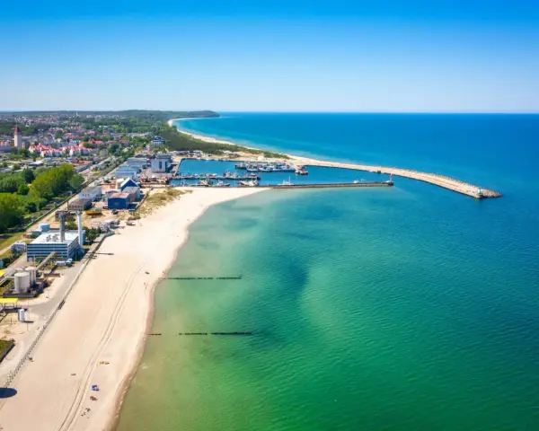 Słoneczna plaża Władysławowo z portem i turkusową wodą Bałtyku.