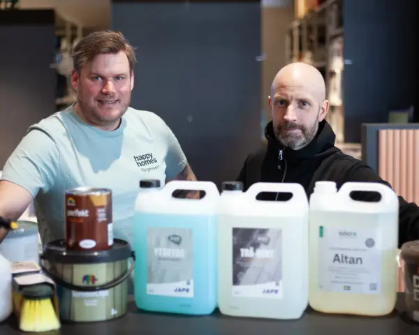 Två män presenterar produkter för att lasera altan. En burk med träolja och flera flaskor med rengöring och skydd.