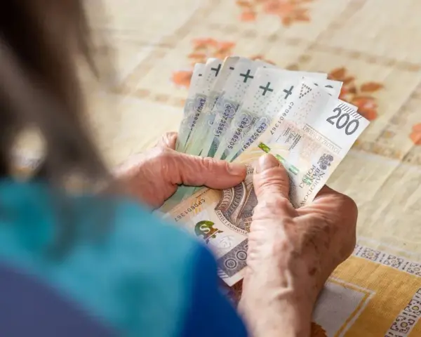 Dłonie starszej osoby liczą banknoty 200 zł. Może to być związane z drugą waloryzacją emerytur, która poprawia byt seniorów.
