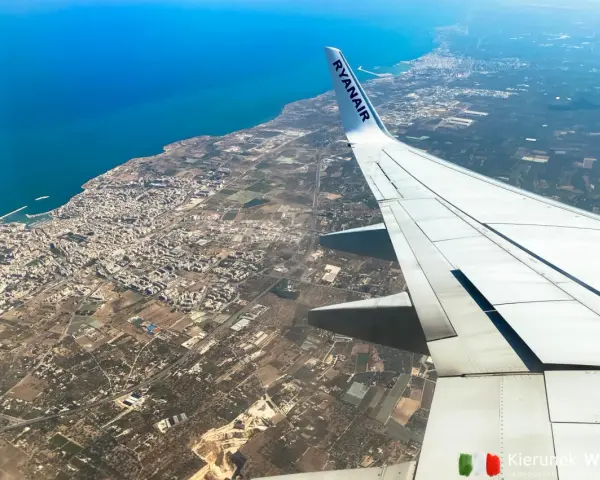 Widok z samolotu Ryanair na wybrzeże i miasto, skrzydło samolotu na pierwszym planie.