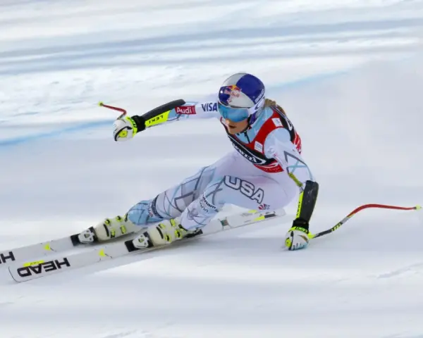 Lindsey Vonn w pełnym pędzie, w białym kombinezonie z napisem USA, na nartach HEAD. Widoczny moment tuż przed upadkiem.
