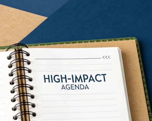 A notebook open to a page titled "HIGH-IMPACT AGENDA," ready for a productive board meeting.
