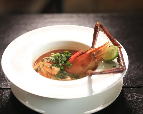 Sopa de marisco con gamba, lima y chile en plato blanco.