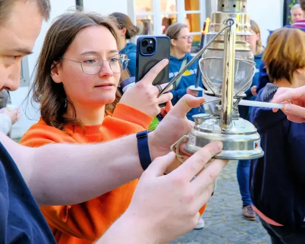 Eine Frau hält ein Handy, während eine Kerze das altenberger licht entzündet.