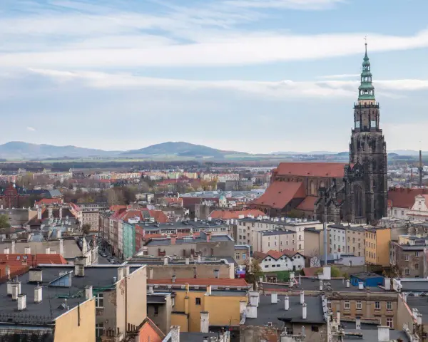 Widok na Świdnicę z górującą nad miastem wieżą katedry. W oddali widać góry. To jedne z głównych świdnica atrakcje.
