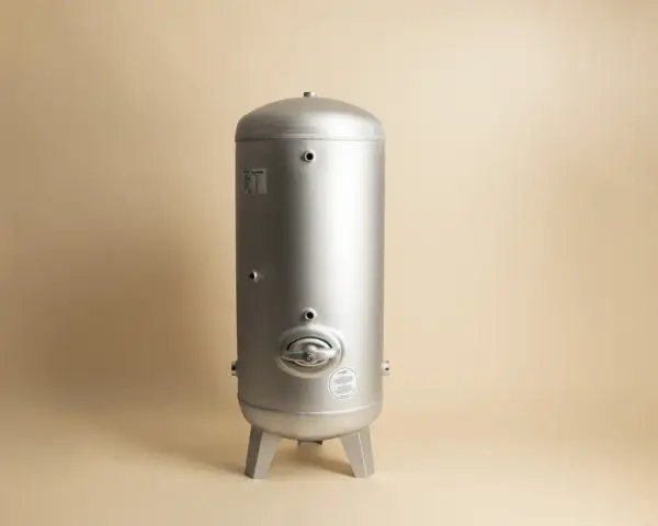 En silverfärgad hydrofor eller hydropress står på tre ben mot en ljusbeige bakgrund.