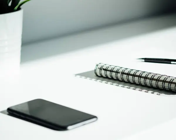A smartphone, notebook, and pen sit on a desk, ready for a startup auditor's analysis.