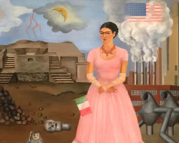 Frida Kahlo w różowej sukni, z flagą Włoch, na tle fabryki Forda i piramidy. Jej niepełnosprawność jest widoczna w jej postawie.