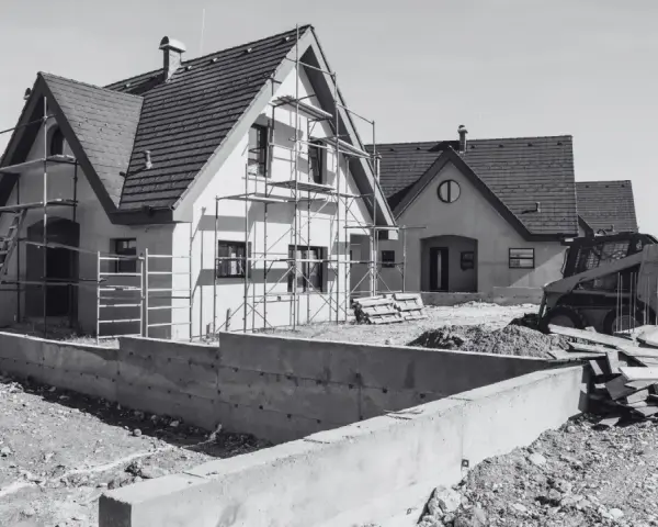 Domy w budowie, rusztowania, koparka i materiały budowlane. Mam pozwolenie na budowę, co dalej? Czas na realizację marzeń o własnym domu.