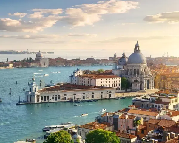 Venice cityscape with canals, boats, and historic buildings under a sunny sky.
