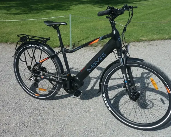 Svart elcykel, modell MOMAS JASON URBAN, redo för ett momas elcykel test. Ställning bak, skärmar och reflexer syns tydligt.