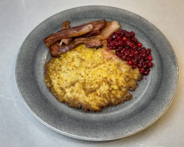 En tallrik med raggmunk, stekt fläsk och lingon. Ett klassiskt svenskt raggmunk recept som är perfekt för en mysig middag.