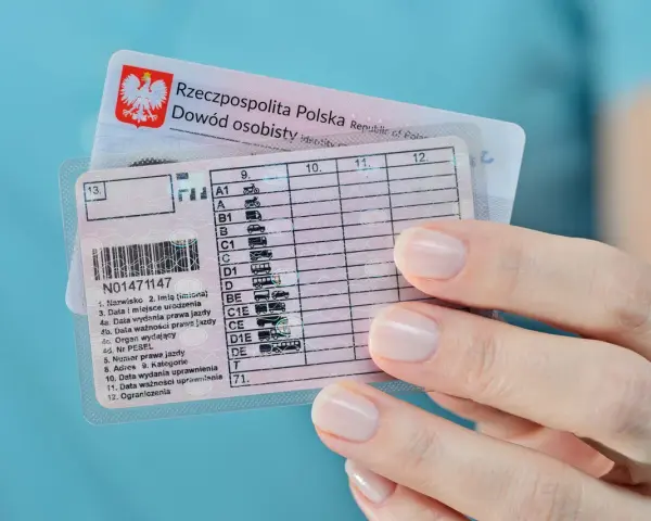 Polskie prawo jazdy z kategoriami, w tym kat. B, w dłoni. Dokumenty do prowadzenia pojazdów.