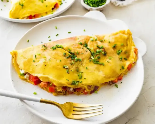Złocisty omlet z białek, nadziany warzywami i serem, posypany szczypiorkiem. Idealny na lekki posiłek.