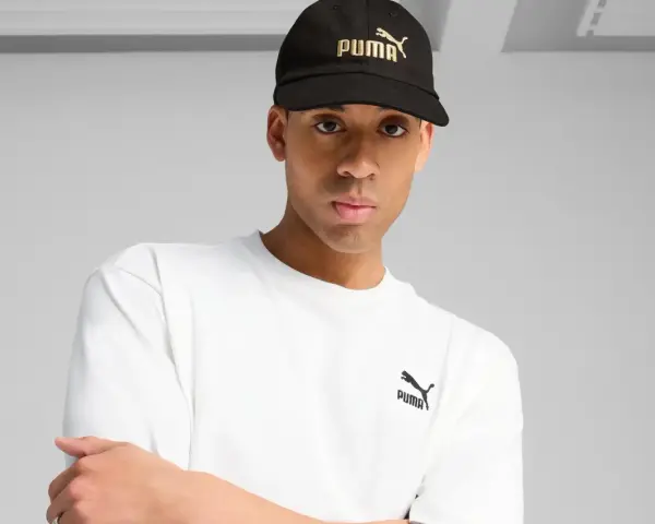 Mężczyzna w czarnej czapce z logo Puma i białej koszulce.