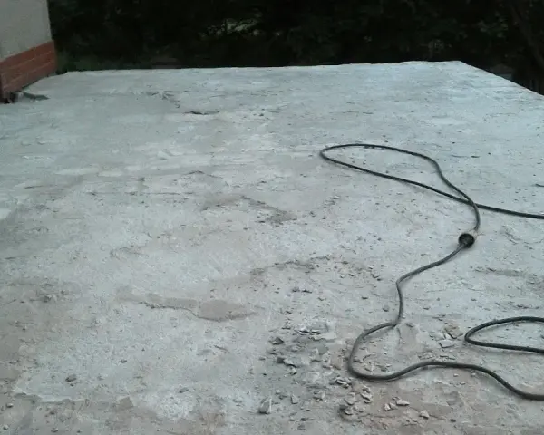 Betonowy taras czeka na remont. Obok leży młot udarowy, gotowy do pracy. Nivoplan pomoże w pracach.