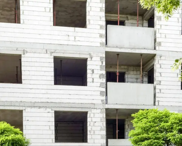 Budowa bloku mieszkalnego, widoczne puste okna i balkony. W przyszłości powstanie tu mieszkanie komunalne.