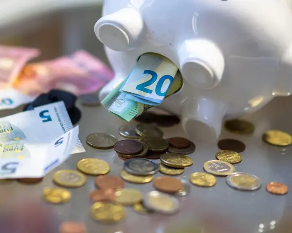Sparschwein mit Euro-Scheinen und Münzen. Vielleicht reicht es bald für free now taxi preise.