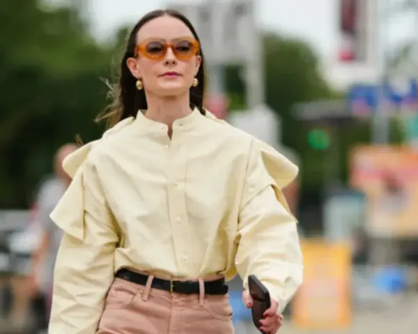 Donna con camicia gialla e pantaloni rosa. Un esempio di pantaloni rosa abbinamenti perfetti per un look casual chic.
