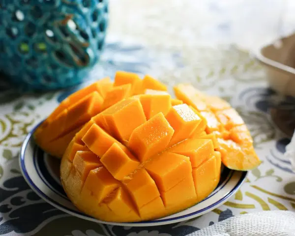 En skål med skivad mango, full av vitaminer, på en duk med mönster.