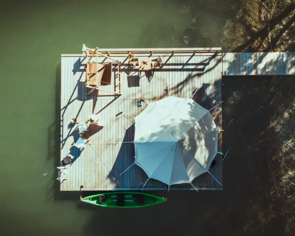 En flytande plattform vid Marholmen camping med tält, solstolar och en grön kajak.