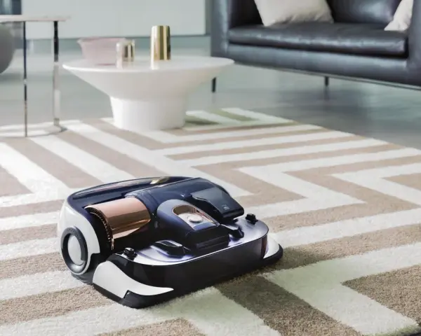 En modern robotdammsugare arbetar på en randig matta i ett stilrent vardagsrum.
