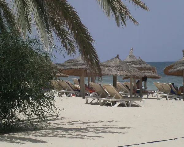 Plaża na Djerbie z leżakami i parasolami. Ludzie odpoczywają, co sugeruje, że na Djerbie jest bezpiecznie.