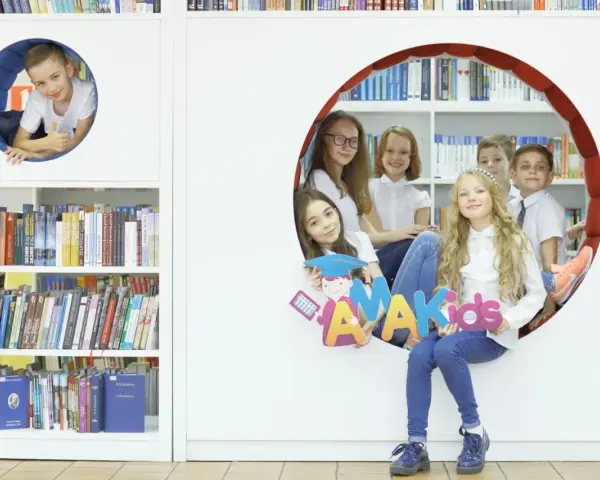 Dzieci z radością pozują z literami "AMAKids" w bibliotece.