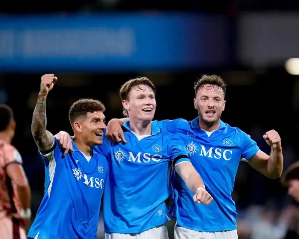 Piłkarze Napoli świętują zwycięstwo nad Hellas Verona. Radość na twarzach zawodników, jeden z nich unosi pięść w geście triumfu.