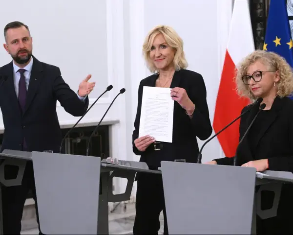 Trzy osoby przy mównicach, w tle flagi Polski i UE. Wibracja związku 8.