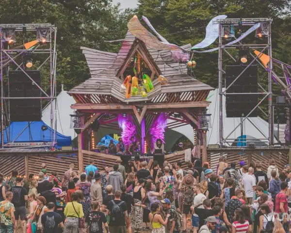 Tłum ludzi na festiwalu **summer contrast festival**. Drewniana scena z dekoracjami, głośniki i światła tworzą magiczną atmosferę.