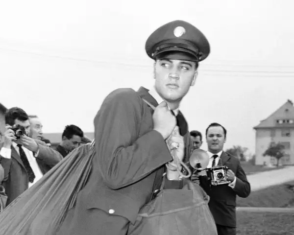 Elvis Presley 1958, in Uniform, wird von Paparazzi umringt, die mit ihren Kameras auf ihn richten.