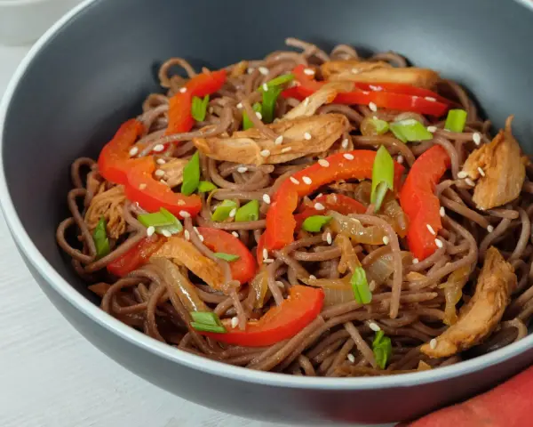 Makaron soba przepis: danie z makaronem gryczanym, kurczakiem, papryką i szczypiorkiem, posypane sezamem.