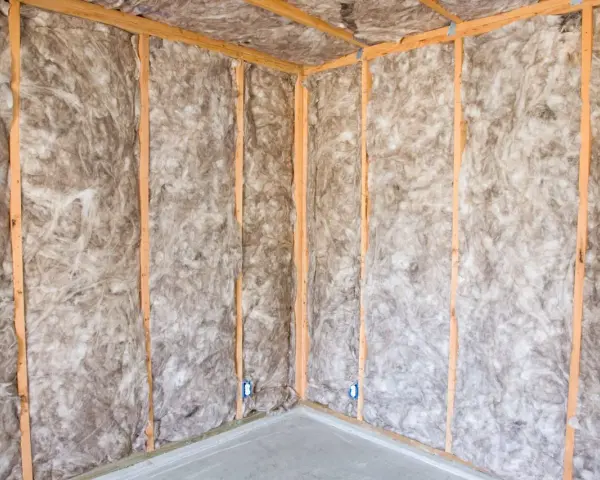Coin d'une pièce en construction, murs et plafond recouverts d'une isolation ouate de cellulose.