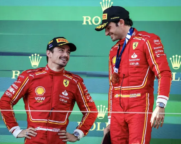 Carlos Sainz, con su altura destacada, sonríe en el podio junto a su compañero.
