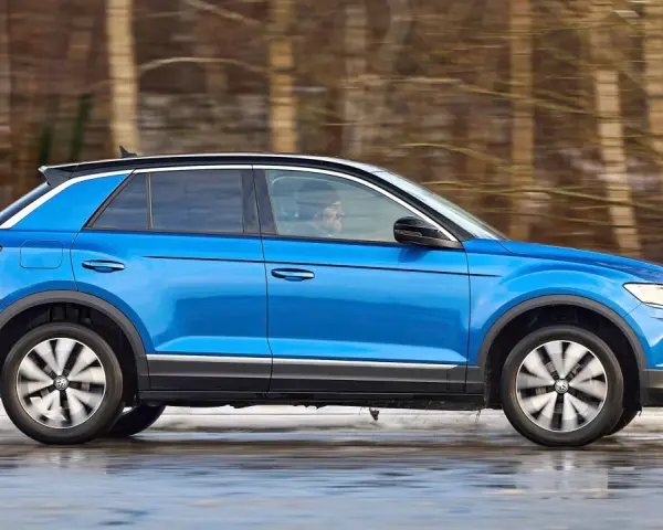 Blauer VW T-Roc fährt durch verschneite Landschaft. Keine Rede von vw t-roc kinderkrankheiten, nur Fahrspaß!