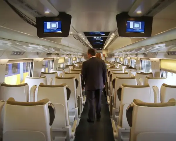 Wnętrze pociągu Pendolino. Para pasażerów idzie przez pusty wagon w drodze z Rzeszowa do Gdańska.